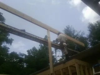 Carpenter setting a ridge beam over a new addition frame — Ice Dam Removal by Roofing Brothers in Batchelor