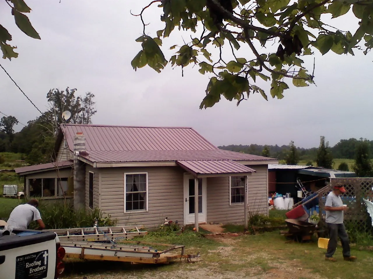 Crew finishing a mauve metal roof on a small farmhouse in Batchelor
