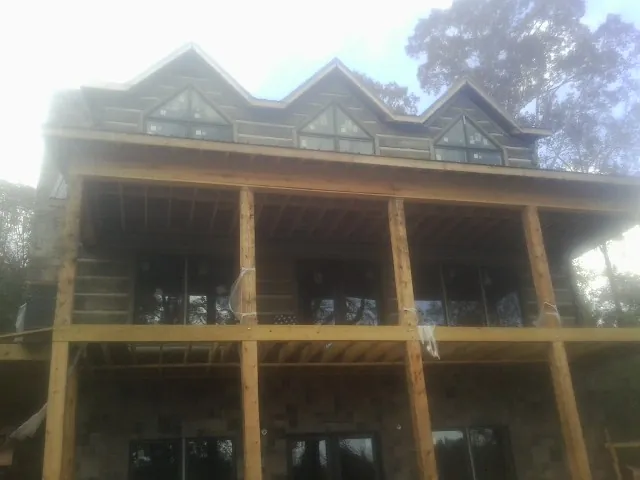 Dormers and porch framing on a large log home under construction — Roof Coating work by our crew in Batchelor