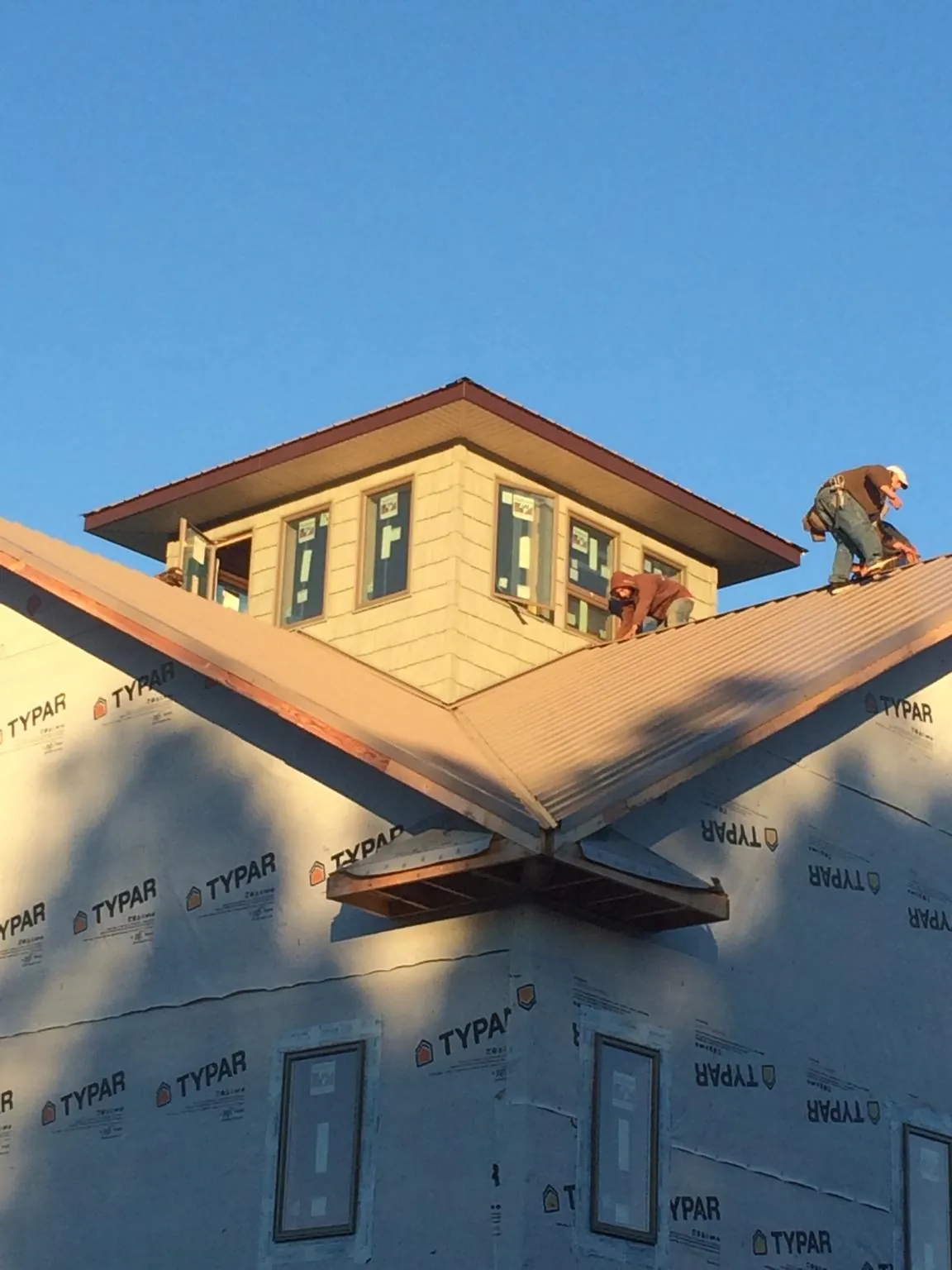 Roofers working around a rooftop cupola on a new metal roof at sunset — Roof Waterproofing in Batchelor by Roofing Brothers